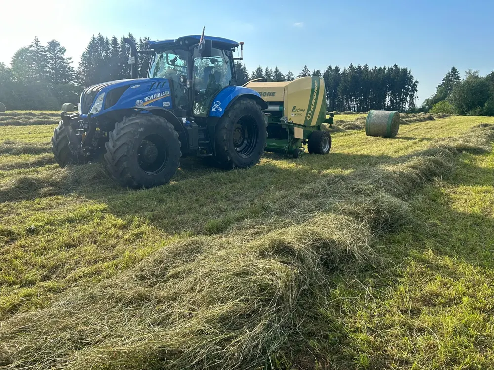 Traktor mit Rundballenpresse auf einer Wiese